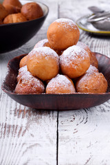 Round donuts topped with sugar powder on white wooden table