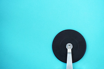 Close-up of pizza cutter on light blue background.