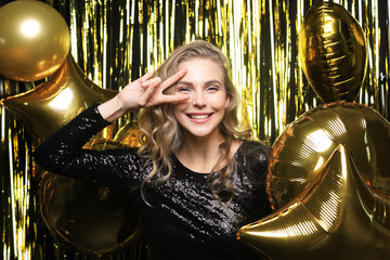 Fototapeta na wymiar Cheerful woman with balloons laughing on gold background.