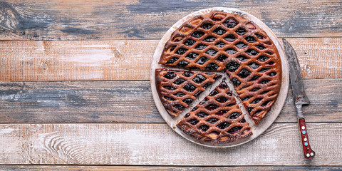 Food banner: homemade open pie with black currant on a rustic background.
