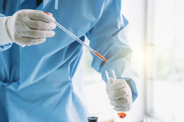 scientist drop red chemical liquid in  tube for experiments test in labatory