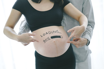 Man and Pregnant Asian Woman with painted brush word on belly - loading and figures 90%