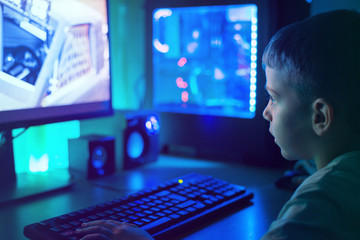 Boy play game on modern PC with RGB lights. Dark scene, close-up. © Stanisic Vladimir