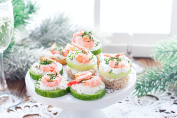 Assorted canapes with shrimps - with fresh cucumbers, cherry tomatoes, bread, crackers on a New Year's table, horizontal