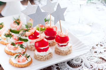 Assorted appetizers canapes with shrimps - with fresh cucumbers, cherry tomatoes, bread, crackers on the festive table, horizontal, copy space