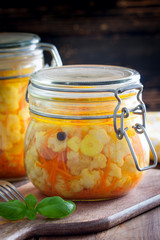 Pickled cauliflower with carrots in glass jars, selective focus