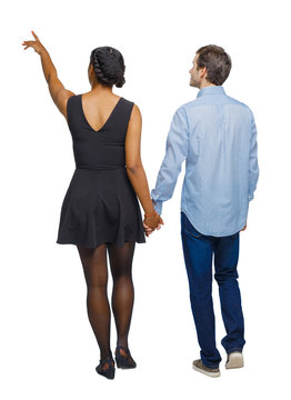  Back view of interracial going couple who points somewhere.