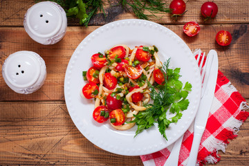 Squid salad with tomato on a white plate, top view, selective focus