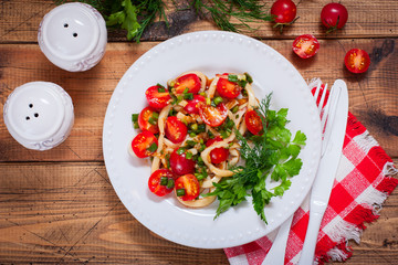 Squid salad with tomato on a white plate, top view, selective focus