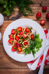 Squid salad with tomato on a white plate, top view, selective focus
