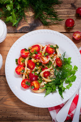 Squid salad with tomato on a white plate, top view, selective focus