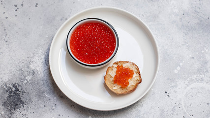 salmon red caviar in a white bowl on a light background. sandwich with red caviar. sea food. top view