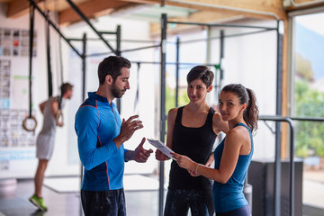 Gym instructor assisting two sporty women  in fitness center.Concept of exercises