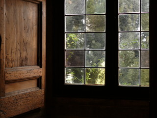 Ancient window with leaded glass and wooden shutters.