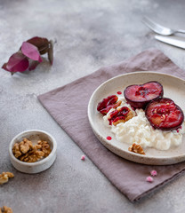 delicious breakfast, yogurt with fruits and nuts in a ceramic plate. gray concrete background