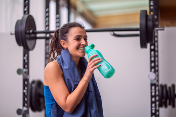 Fototapeta na wymiar Smiling sports girl drinks water sitting