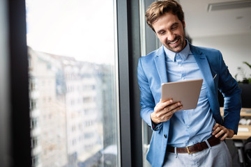 Portrait of businessman smiling while using digital tablet