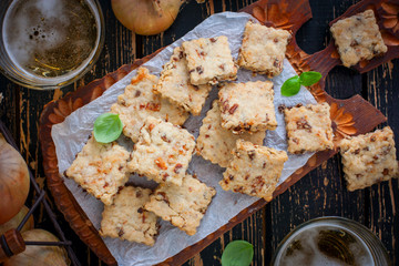 Cracker cookies with fried onions on a wooden board with a glass of beer, horizontal, top view