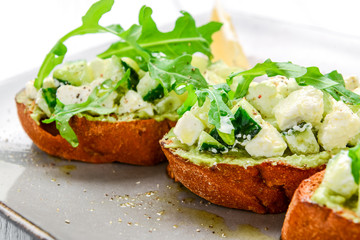Tasty savory Italian appetizers, or bruschetta, on slices of toasted baguette garnished with basil