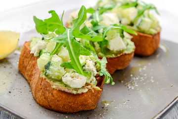 Tasty savory Italian appetizers, or bruschetta, on slices of toasted baguette garnished with basil