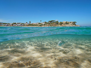 Spain Costa Brava, Mediterranean coastline near Palamos town with sand and fish underwater sea, split view over and under water surface, Catalonia, La Fosca