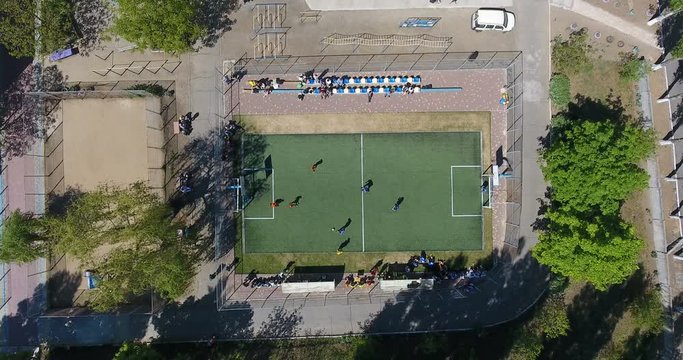 Aerial view of green soccer field with children players at school stadium
