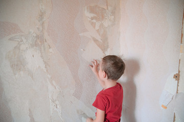 Home renovation, room wall repairing, young boy removing old wallpaper