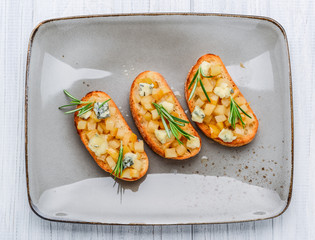 Tasty savory Italian appetizers, or bruschetta, on slices of toasted baguette garnished with basil