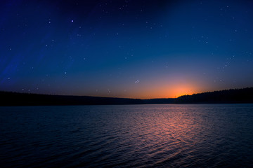 Naklejka na ściany i meble sunset with starry sky over a lake