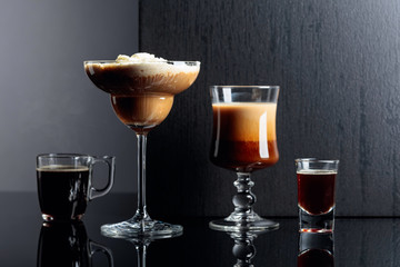 Coffee cocktails, espresso and coffee liquor on black reflective background.