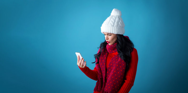 Young woman with Christmas theme using her phone on a blue background