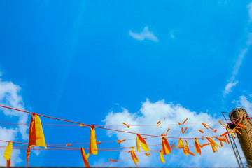 Seil mit orangen Wimpen vor Himmel und Schornstein