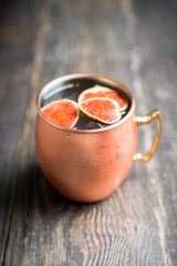 Moscow mule cocktail with figs and thyme on the rustic background. Selective focus. Shallow depth of field.