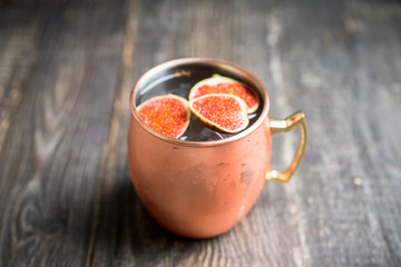 Moscow mule cocktail with figs and thyme on the rustic background. Selective focus. Shallow depth of field.
