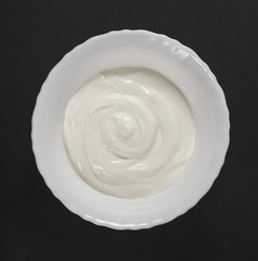 Dishes of Ukrainian national cuisine, including dumplings with fried onions and sour cream, are served in white dishes on a black background and decorated with almonds.