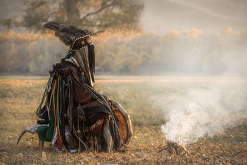 Mongolian traditional shaman performing a traditional shamanistic ritual with a drum and smoke in a...