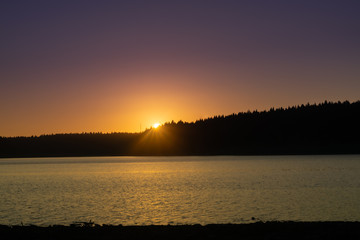 Vivid orange sunset over mountains and calm water