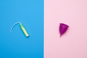 Different types of feminine hygiene products - menstrual cup and tampons on pink and blur background. Selective focus