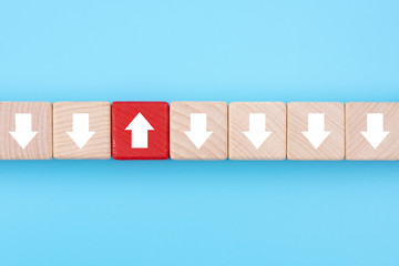 Red wooden block with arrow facing individual pointing in the different way on blue background,...