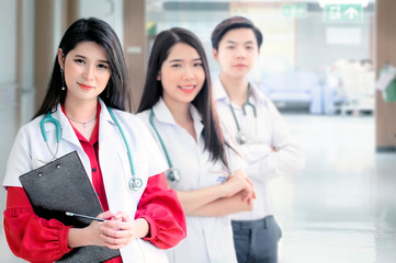 Fototapeta premium Portrait of three young doctors with stethoscope looking at camera while standing at ward in hospital.