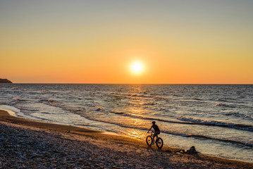 Beautiful sunset on the sea. Baltic sea at sunset, Toila, Estonia. Toila - seaside resort and popular holiday destination in Estonia. Cyclist on the beach.