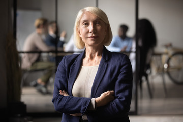 Confident successful mature old businesswoman look at camera in office