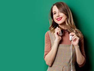 woman in vintage dress with headphones on green background