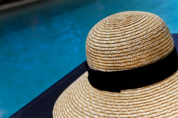 Fototapeta na wymiar Straw hat beside a pool