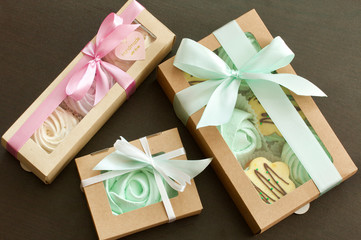 Marshmallows of different shapes and colors. Stacked in paper craft packaging. Tied with colored satin ribbons.