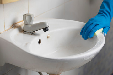 Cleaning service hand in blue rubber gloves cleaning bathroom
