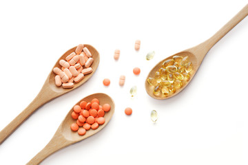 healthy vitamin supplement capsules in a spoons on white background.