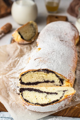 Poppy seed roll or strudel on wooden board sprinkled with powdered sugar. Traditional polish festive pastry – Makowiec.
