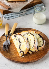 Poppy seed roll or strudel on wooden board sprinkled with powdered sugar. Traditional polish festive pastry – Makowiec.
