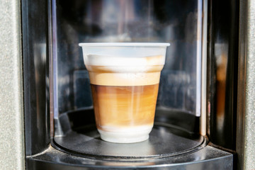 Appetizing coffee in a plastic cup from the machine. Close-up.